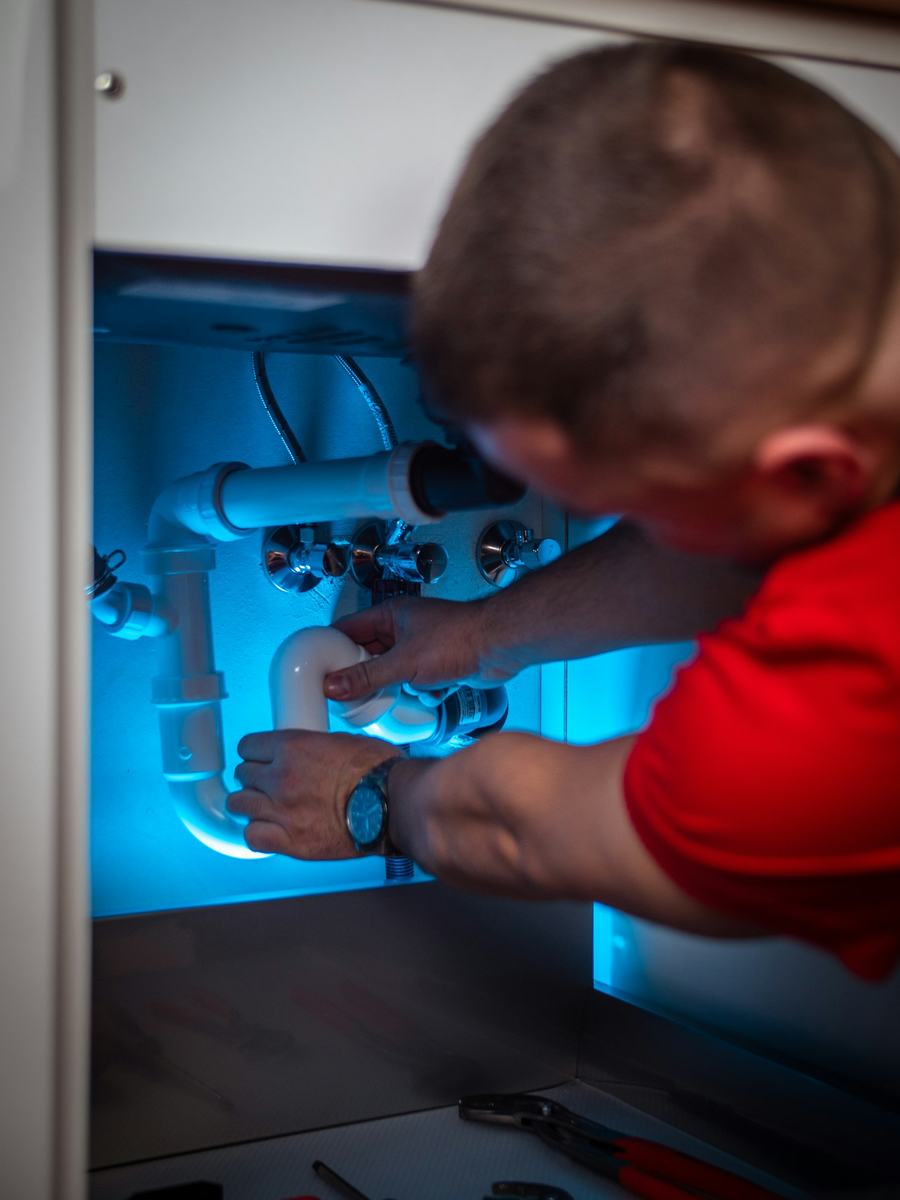 Plumber repairing the drain and supply lines under a kitchen sink