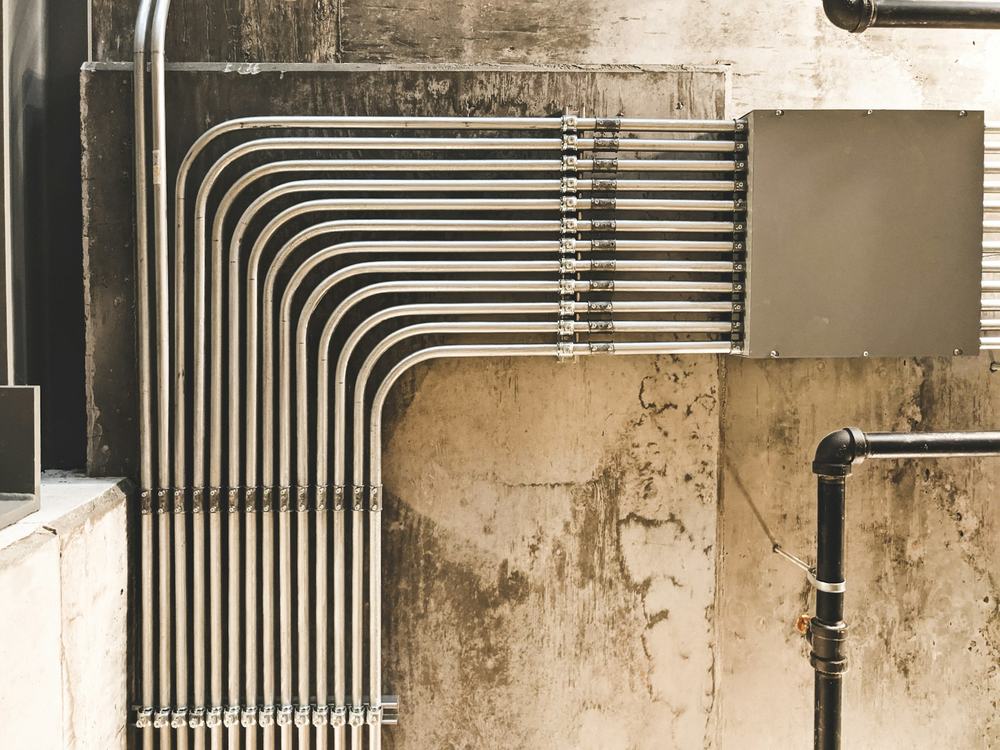 Rows of metal pipes running along a commercial building wall