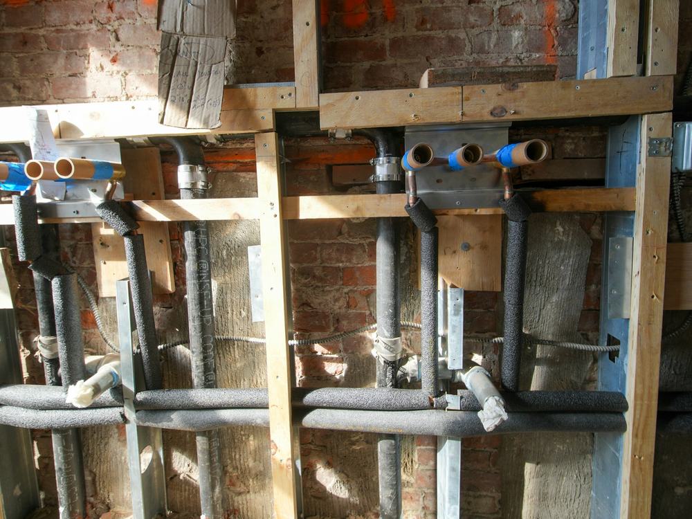 Exposed copper and PEX water supply lines inside an open wall