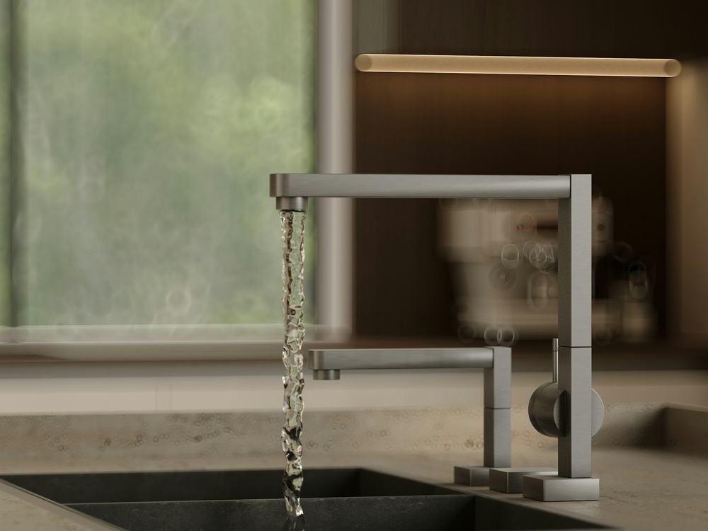Clear water flowing from a modern stainless kitchen faucet